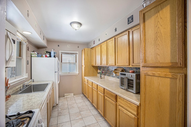 kitchen featuring white fridge, light tile patterned floors, sink, range, and tasteful backsplash