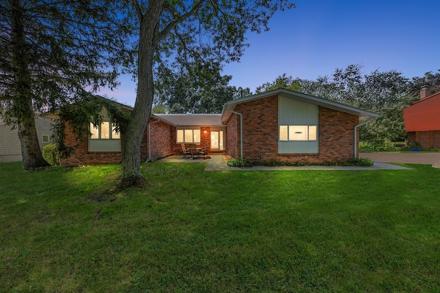 mid-century inspired home featuring a patio, brick siding, and a lawn