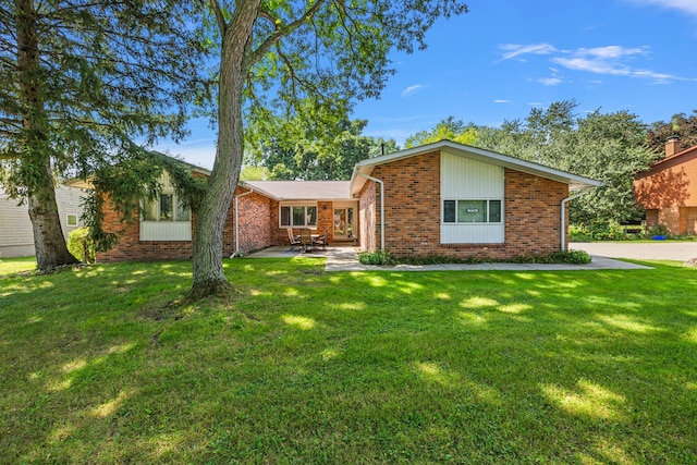 view of front of house with brick siding, a patio, and a front lawn