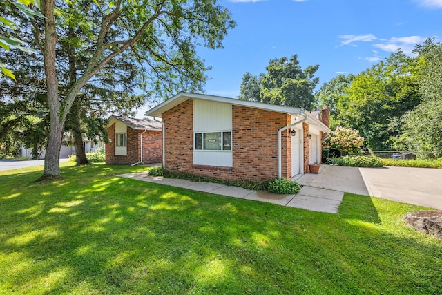 view of front of home featuring brick siding, a chimney, concrete driveway, a garage, and a front lawn