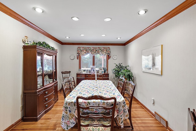 dining room with light wood finished floors, visible vents, and crown molding