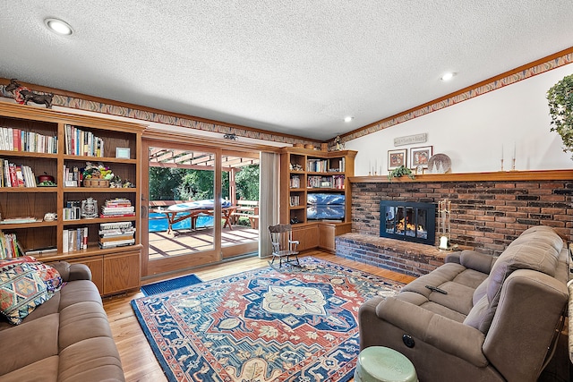 living area with light wood-type flooring, a fireplace, vaulted ceiling, and a textured ceiling