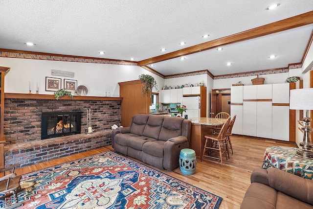 living room with a textured ceiling, lofted ceiling with beams, a fireplace, and light wood-style flooring