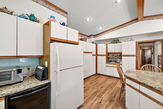 kitchen featuring vaulted ceiling with beams, wood finished floors, freestanding refrigerator, and white cabinetry