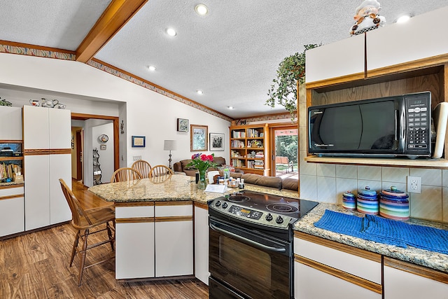 kitchen featuring white cabinets, wood finished floors, vaulted ceiling with beams, a peninsula, and black appliances