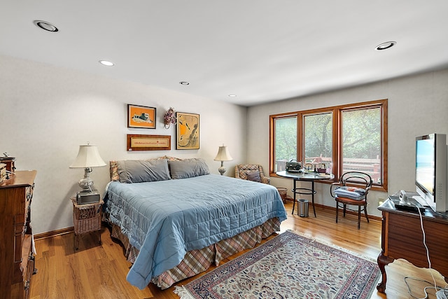 bedroom featuring baseboards, wood finished floors, and recessed lighting