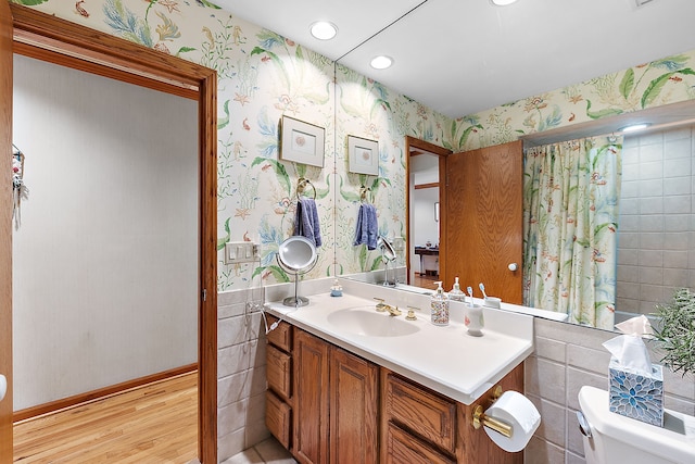 bathroom featuring vanity, wood finished floors, toilet, and wallpapered walls