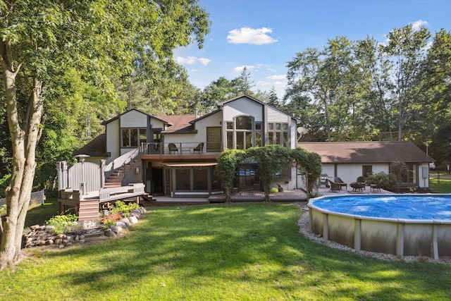 rear view of house featuring a lawn and a swimming pool side deck