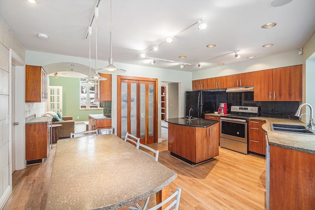 kitchen with stainless steel electric range oven, sink, black fridge, decorative light fixtures, and a kitchen island with sink