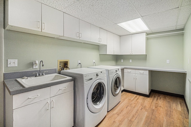 laundry room with cabinets, sink, separate washer and dryer, and light wood-type flooring