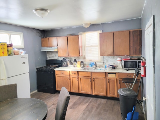 kitchen with sink, black gas stove, white refrigerator, dark wood-type flooring, and decorative backsplash