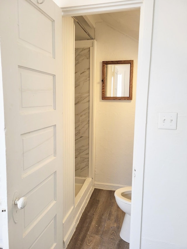 bathroom with toilet, hardwood / wood-style flooring, and a tile shower