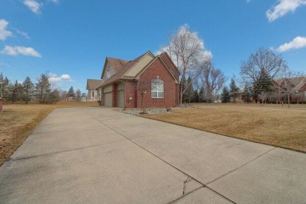 view of front facade featuring a garage, a front yard, concrete driveway, and brick siding