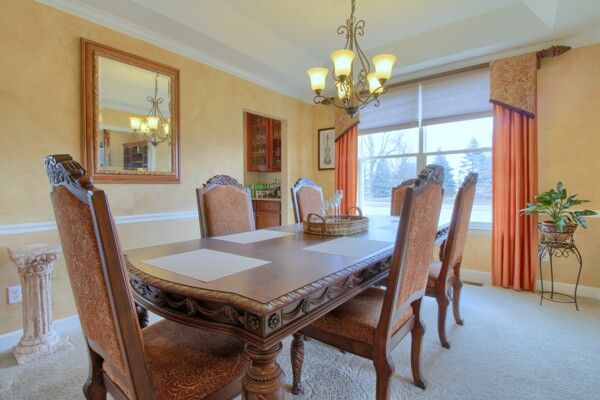 dining room featuring a chandelier, light carpet, baseboards, ornamental molding, and a tray ceiling