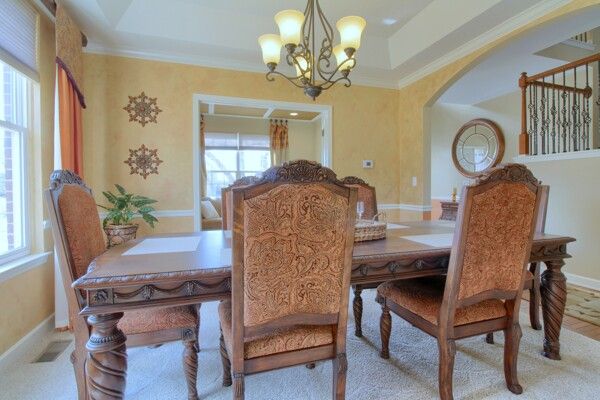 9077 Chambord Dr, Ypsilanti, MI 48197 - dining area featuring arched walkways, a notable chandelier, a raised ceiling, and crown molding
