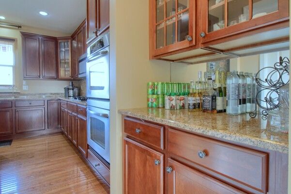 kitchen featuring a healthy amount of sunlight, light stone countertops, glass insert cabinets, and light wood-style floors