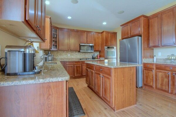 9077 Chambord Dr, Ypsilanti, MI 48197 - kitchen featuring a sink, stainless steel appliances, light wood-style flooring, and brown cabinetry