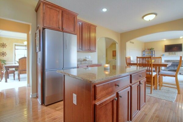 kitchen with light wood finished floors, arched walkways, a kitchen island, freestanding refrigerator, and light stone countertops