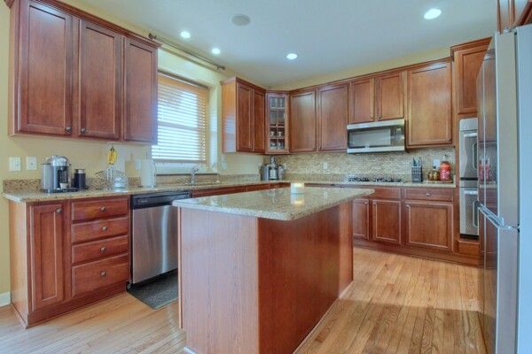 kitchen featuring stainless steel appliances, a center island, light wood-style flooring, and light stone countertops