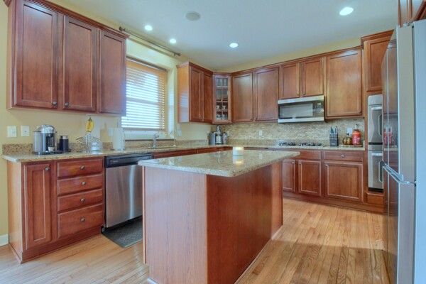 9077 Chambord Dr, Ypsilanti, MI 48197 - kitchen featuring light wood finished floors, light stone countertops, appliances with stainless steel finishes, and a center island