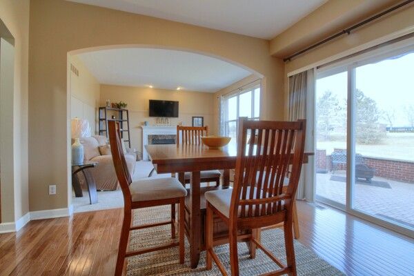 dining area with baseboards, a fireplace, arched walkways, and wood finished floors