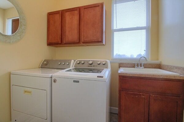 clothes washing area with cabinet space, washing machine and dryer, and a sink