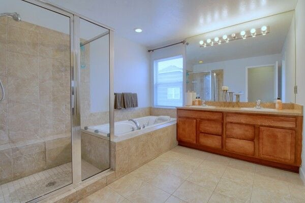 bathroom with double vanity, a sink, a shower stall, and a bath