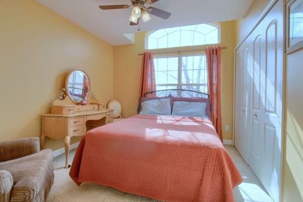 bedroom with light carpet and a ceiling fan