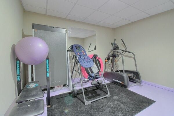 workout area with a paneled ceiling and baseboards