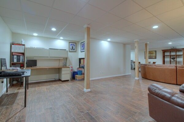 interior space featuring baseboards, a drop ceiling, wood finished floors, and recessed lighting