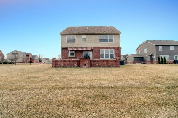 rear view of property with brick siding and a lawn