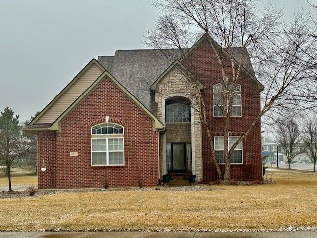 view of front of property with a front yard, brick siding, and stone siding