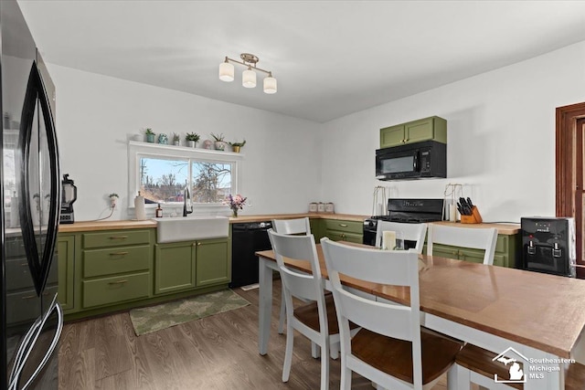 kitchen featuring sink, black appliances, green cabinets, and dark hardwood / wood-style floors