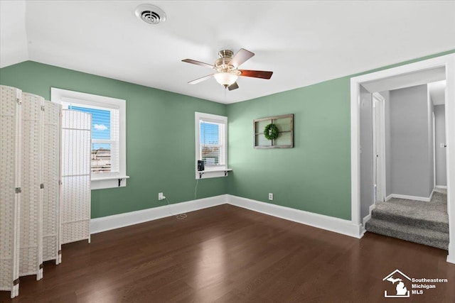 unfurnished bedroom featuring multiple windows, vaulted ceiling, dark wood-type flooring, and ceiling fan