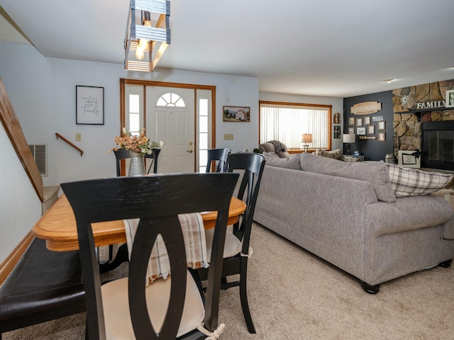 carpeted dining space with a stone fireplace