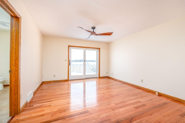 empty room featuring ceiling fan, light hardwood / wood-style floors, and a textured ceiling