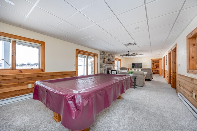 rec room featuring a fireplace, light carpet, wood walls, and a baseboard radiator