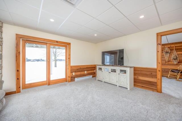 living room featuring a paneled ceiling, light carpet, wood walls, and baseboard heating