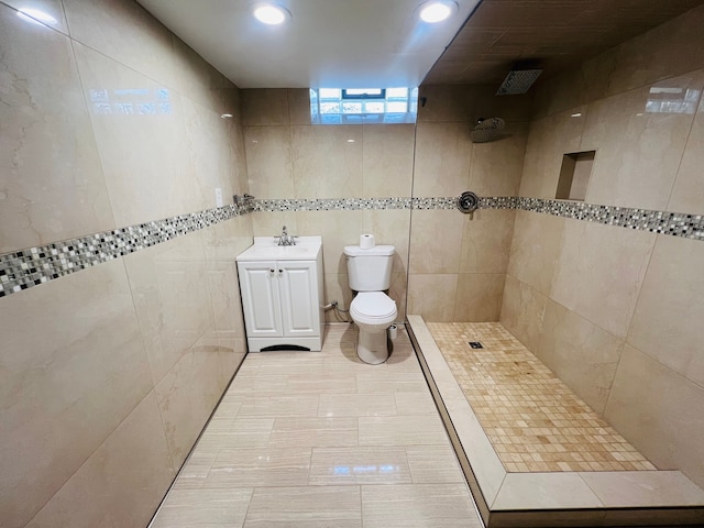 full bathroom featuring toilet, a tile shower, vanity, tile walls, and recessed lighting