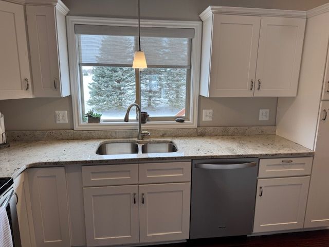 kitchen with white cabinetry, dishwasher, light stone counters, and sink