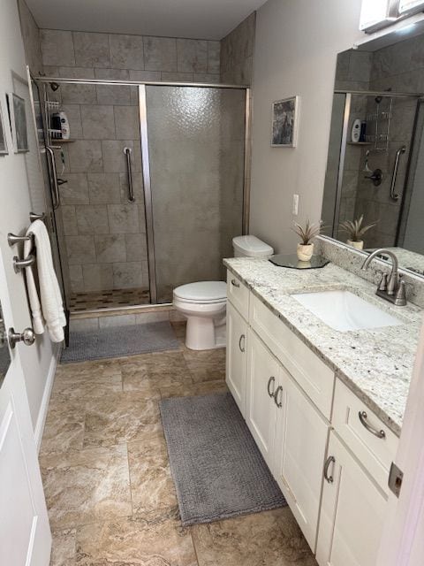 bathroom featuring vanity, a shower with door, and toilet