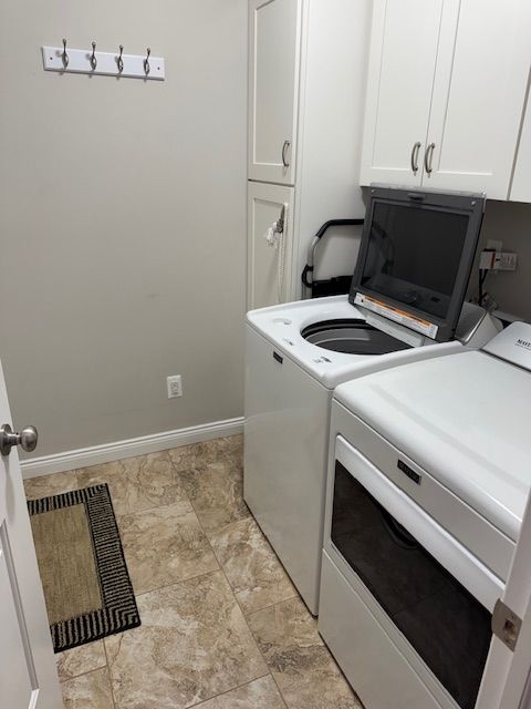 clothes washing area with washer and dryer and cabinets