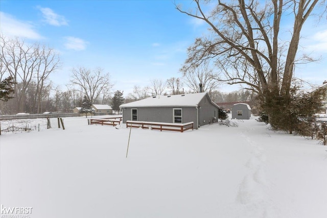 snow covered back of property with a shed