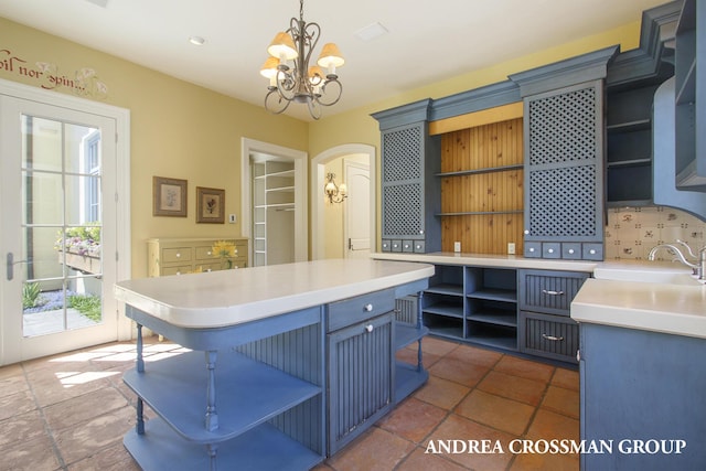 kitchen with blue cabinetry, hanging light fixtures, a breakfast bar, sink, and a chandelier