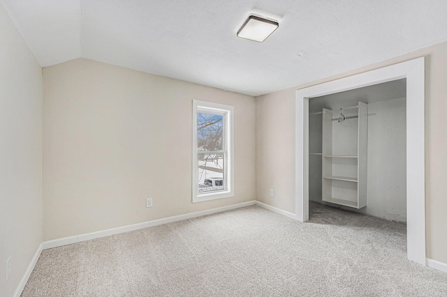 unfurnished bedroom with a textured ceiling, a spacious closet, light colored carpet, and a closet