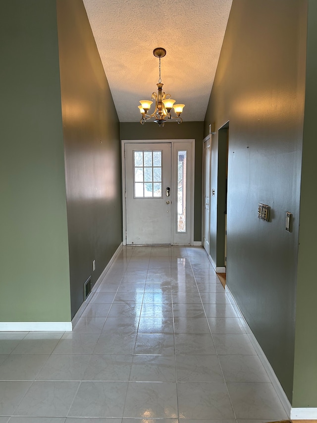 tiled foyer featuring vaulted ceiling, an inviting chandelier, and a textured ceiling