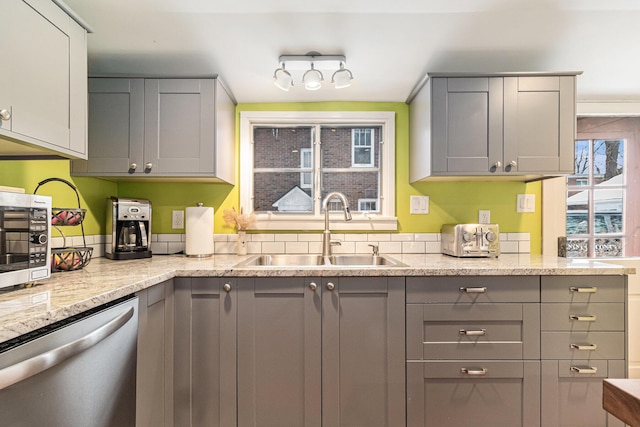 kitchen featuring stainless steel appliances, sink, gray cabinetry, and light stone counters