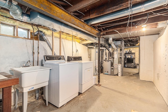 basement with washing machine and clothes dryer, sink, water heater, and heating unit