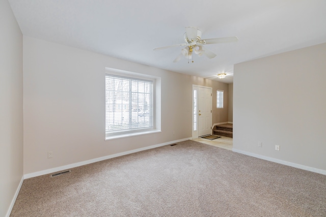 empty room with visible vents, ceiling fan, light carpet, and baseboards