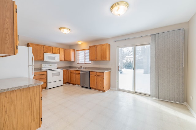 kitchen with light countertops, white appliances, light floors, and a sink